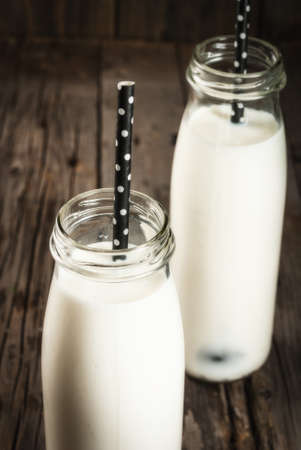 Two bottles of organic rustic milk on an old wooden table. Copy space close viewの写真素材