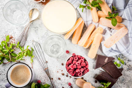 Cooking Italian food dessert Tiramisu, with all the necessary ingredients cocoa, coffee, mascarpone cheese, mint and raspberries, on grey stone background.  Copy space  top viewの写真素材