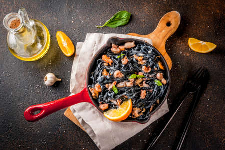 Modern italian dinner, Mediterranean food, black cuttlefish ink spaghetti pasta with seafood, olive oil and basil,  on grey stone table  copy spaceの写真素材