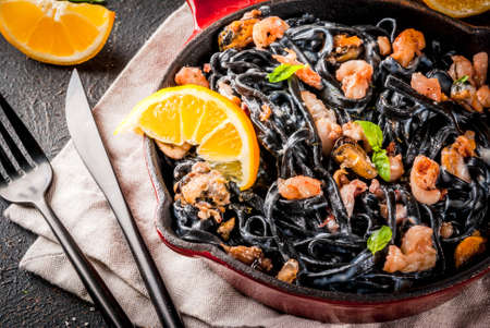 Modern italian dinner, Mediterranean food, black cuttlefish ink spaghetti pasta with seafood, olive oil and basil,  on dark rusty table copy spaceの写真素材