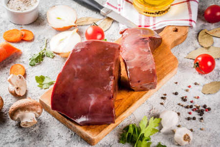 Raw beef liver with spices, herbs and vegetables, grey stone table copy spaceの写真素材