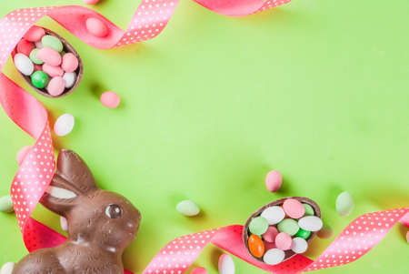 Easter holiday greeting card background, with chocolate easter bunny, candy eggs, quail eggs and...