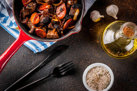 Roasted or grilled beef liver with onion and carrot in portioned frying pan, dark rusty  table copy space top viewの写真素材