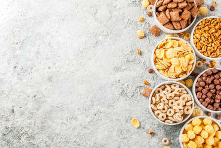 Set of various breakfast cereal corn flakes, puffs, pops, grey stone table copy space top viewの写真素材