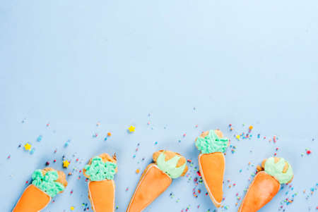 Easter holiday concept, sweet cookies in form of carrots, Easter bunny, with sweet sprinkles, light blue background copy space top view, greeting card backgroundの写真素材