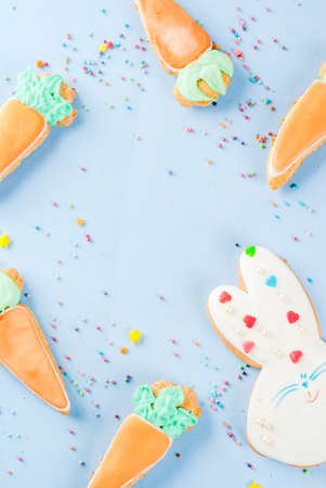 Easter holiday concept, sweet cookies in form of carrots, Easter bunny, with sweet sprinkles, light blue background copy space top view, greeting card backgroundの写真素材