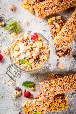 Healthy breakfast and snack concept, homemade granola with fresh raspberries in jar and nuts and granola bars, on grey stone stone background copy space top viewの写真素材