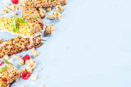 Healthy breakfast and snack concept, homemade granola with fresh raspberries and nuts and granola bars, on bright blue background copy space の写真素材