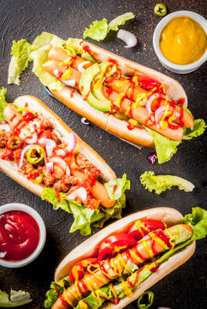 Assortment of different homemade hot dogs with sausage, fried onion, tomatoes and beans, dark rusty background copy space top viewの写真素材