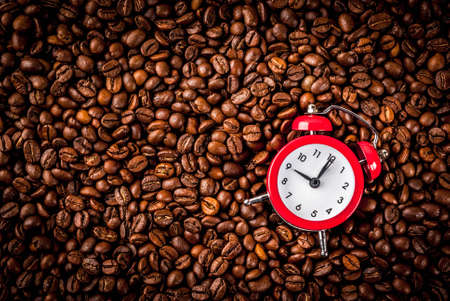 Concept of a cheerful, good start to the day, morning coffee. Dark rusty background with coffee beans, an alarm clock and a cup of coffee. Top view copy spaceの写真素材