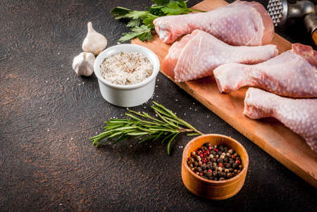 Raw meat, chicken legs, with herbs and spices n dark rusty background, copy spaceの写真素材