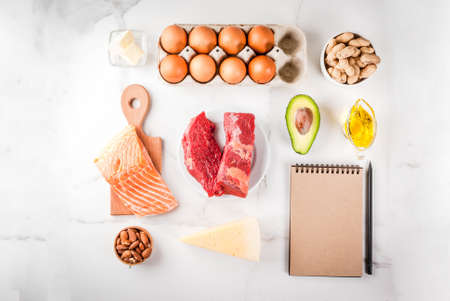 Ketogenic low carbs diet concept. Healthy balanced food with high content of healthy fats. Diet for the heart and blood vessels. Organic ingredients, white background, copy space top view, notepad の写真素材
