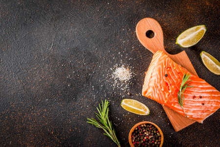 Fresh raw fish salmon, steak fillet, with spices, lime, rosemary, salt, on a dark rusty background, copy space top viewの写真素材