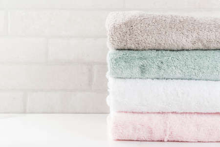Spa relax and bath concept, stack clean bath towels colorful cotton terry textile in bathroom white background, copy space top viewの写真素材