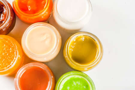 Variety of homemade baby vegetable and fruit puree,  white marble background copy space top viewの写真素材