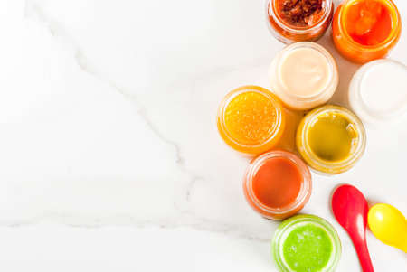 Variety of homemade baby vegetable and fruit puree,  white marble background copy space top viewの写真素材