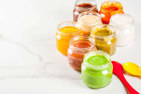 Variety of homemade baby vegetable and fruit puree,  white marble background copy spaceの写真素材