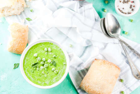 Green pea soup with fresh bread on light blue concrete table, copy space top viewの写真素材