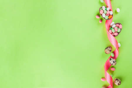 Easter holiday greeting card background, with chocolate easter bunny, candy eggs, quail eggs and festive ribbon, copy space top viewの写真素材