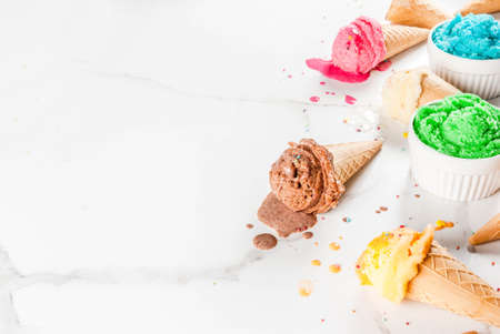 Different homemade melting ice cream in bowls and waffle ice cream cones, white vanilla, orange,...