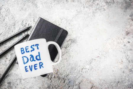 Father's Day concept, background for congratulating cards with a cup with the inscription Best Father ever, business notebook and pencils. copy space top viewの写真素材