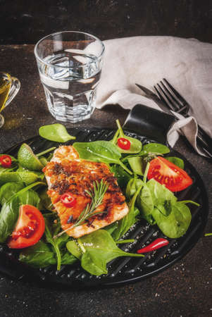Grilled salmon steak filet with fresh vegetables, spinach and lime, dark rusty table copy spaceの写真素材