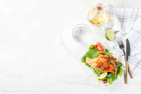 Grilled salmon steak filet with fresh vegetables, spinach and lime, white marble table copy space top viewの写真素材