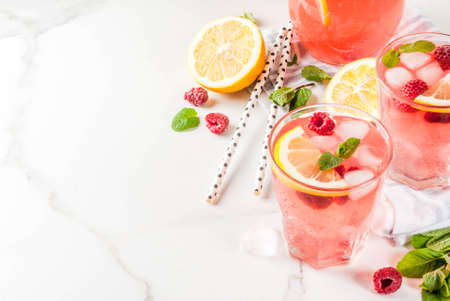 Summer refreshing drinks, fruit and berry raspberry mojito or lemonade with fresh mint, frozen raspberries, slices of lemon, ice, on a light background. copy spaceの写真素材
