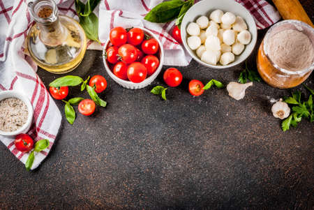 Homemade pasta pizza italian food ingredient on dark rusty table with flour, olive oil, basil, tomatoes and kitchen accessories top viewの写真素材