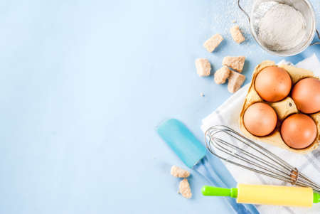Ingredients and utensils for cooking baking egg, flour, sugar, whisk, rolling pin, on blue...