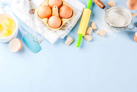 Ingredients and utensils for cooking baking egg, flour, sugar, whisk, rolling pin, on blue...