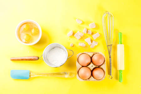 Ingredients and utensils for cooking baking egg, flour, sugar, whisk, rolling pin, on bright yellow background, top viewの写真素材