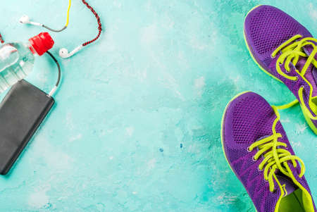 Sports, fitness concept. Running sneakers, water bottle, headphones, dumbbells, smartphone, on a light blue background top view copy spaceの写真素材