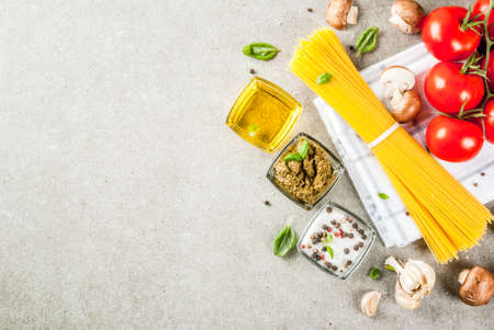 Food background, ingredients for cooking dinner.  Pasta spaghetti, vegetables, sauces and spices, grey stone background copy space top viewの写真素材