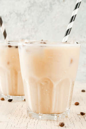 Summer cold Iced coffee frappe with milk and ice cubes, light concrete background copy space