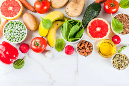 Healthy food background, trendy Alkaline diet products - fruits, vegetables, cereals, nuts. oils, white marble background above copy spaceの写真素材