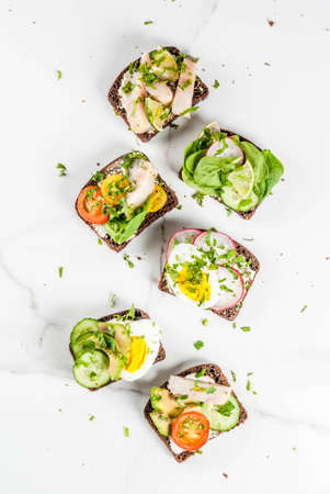 Set of various danish open sandwiches Smorrebrod with fish, egg and fresh vegetables, white marble...