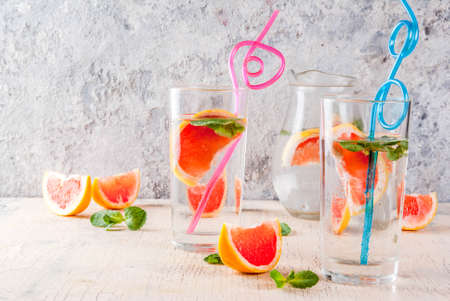 Summer refreshment detox water drink with Pink grapefruit and fresh mint, spa fruit water, lemonade or jin tonic cocktail, light concrete background copy spaceの写真素材