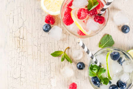 Various berry lemonade or mojito cocktails, fresh iced lemon lime raspberry blueberry infused water,...