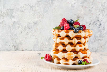 Belgian waffles with raspberries, blueberries and syrup, homemade healthy breakfast, light concrete...