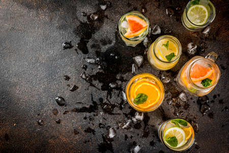 Summer healthy cocktails, set of various citrus infused waters, lemonades or mojitos, with lime lemon orange grapefruit, diet detox beverages, in different glasses dark background copy space aboveの写真素材