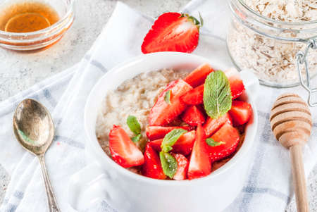 Healthy summer breakfast, overnight oatmeal with fresh strawberry and milk, grey stone backgroundの写真素材