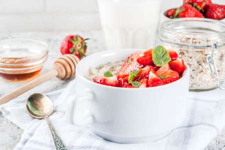 Healthy summer breakfast, overnight oatmeal with fresh strawberry and milk, grey stone backgroundの写真素材