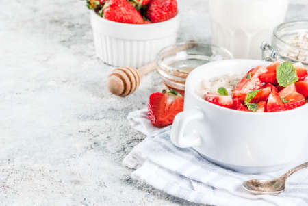 Healthy summer breakfast, overnight oatmeal with fresh strawberry and milk, grey stone backgroundの写真素材