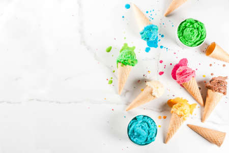 Different homemade melting ice cream in bowls and waffle ice cream cones, white vanilla, orange,...