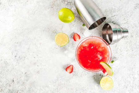 Cold strawberry margarita cocktail with ice, lime and fresh berries in margarita glass, light grey background copy space aboveの写真素材