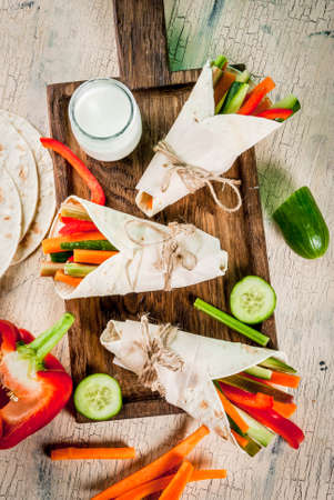 Summer healthy snack appetizer, Mexican style tortilla sandwich wraps assorted colorful fresh vegetable sticks (celery, rhubarb, pepper, cucumber and carrot) with yoghurt sauce dip aboveの写真素材