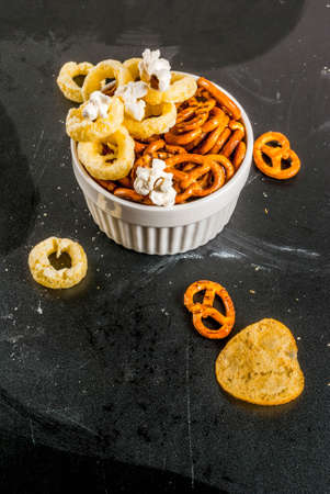 Variation different unhealthy snacks crackers, sweet salted popcorn, tortillas, nuts, straws,...