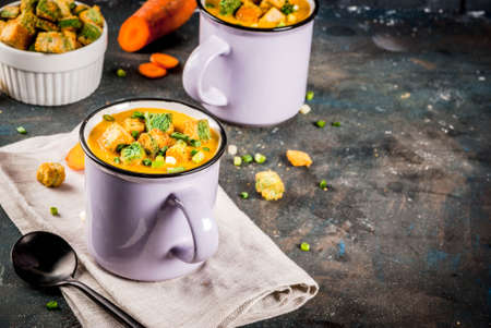 Homemade pureed carrot cream soup, with bread crackers, fresh herbs and cream. On a dark blue background,の写真素材
