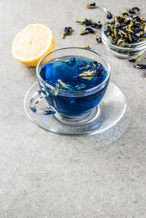 Healthy drinks, organic blue butterfly pea flower tea with limes and lemons, grey concrete background copy spaceの写真素材